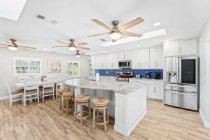 a kitchen with white cabinets and a large island with bar stools at 445 Watts Way in Cocoa Beach