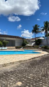 a swimming pool in front of a house with palm trees at Vivenda Hotel in Arapiraca