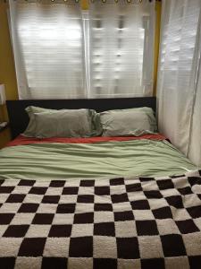 a bed with a checkered blanket in front of a window at Yellow Cactus Oasis in White Water