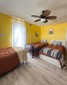 a bedroom with two beds and a ceiling fan at Yellow Cactus Oasis in White Water