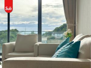 a living room with a couch and a large window at Modern Haven Suite in Hat Yai in Ban Thung Ngai