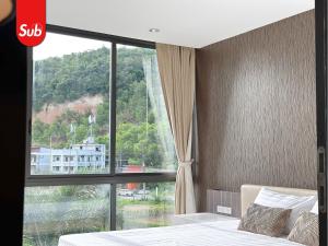 a hotel room with a large window and a bed at Modern Haven Suite in Hat Yai in Ban Thung Ngai