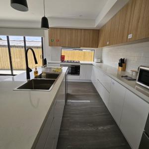 a kitchen with white cabinets and a sink in it at Maruve Guesthouse Plus- Modern Stay near Melb Airport 12 min in Melbourne