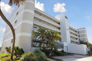 un bâtiment blanc avec des palmiers devant dans l'établissement Boardwalk 401, à Cocoa Beach