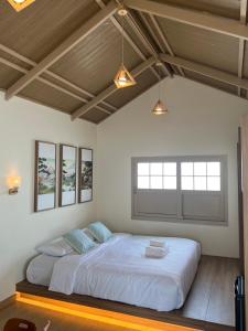 une chambre avec un grand lit blanc dans une pièce dans l'établissement Kiyomizu Onsen & Glamping Resort Saraburi, à Ban Nong Nak