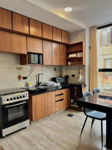 a kitchen with wooden cabinets and a table and a stove at Excelente ubicación, cálido, siéntete en casa in La Paz