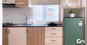 a kitchen with a green refrigerator and a sink at Jarrdin Apartment by CozyNest Syariah in Bandung
