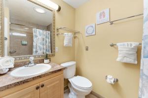 een badkamer met een wastafel, een toilet en een spiegel bij 253 Palm Ln in Cocoa Beach +29 foto's