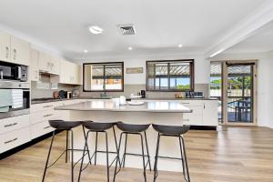 eine Küche mit weißen Schränken und eine große Insel mit Barhockern in der Unterkunft Helena Grand Estate Hunter Valley in Ellalong