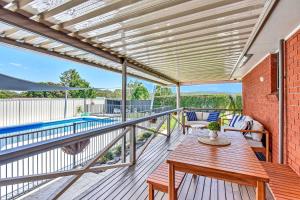 eine Terrasse mit einem Holztisch und Stühlen auf einer Terrasse in der Unterkunft Helena Grand Estate Hunter Valley in Ellalong