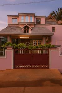 a pink house with a brown garage door at Aswin's Homestay 1bhk in Podanūr