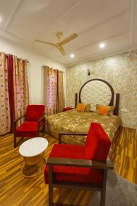 a bedroom with a bed and a red chair at The Shesh Bagh Boutique - Garden Stay Near Dal Lake & Mughal Garden in Srinagar +10 photos