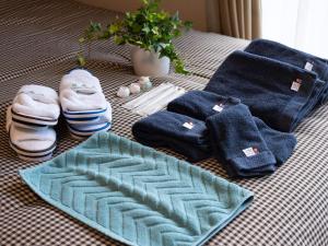 ein Bett mit blauen Handtüchern und Paaren von Schuhen und Handtüchern in der Unterkunft The Global West in Niihama + 117 Fotos