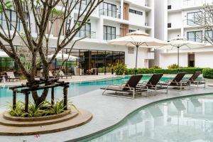 a swimming pool with chairs and a tree next to a building at Laya Resort -Tropical Studio in Layan Beach