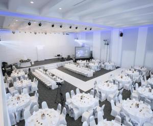 une salle de banquet avec des tables et des chaises blanches et un paravent dans l'établissement The Vista Hotel By Satit Group, à Sadao