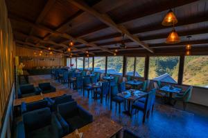 un restaurante con sillas azules, mesas y ventanas en Hotel White Flower, en Jāmb