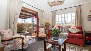 ein Wohnzimmer mit einem roten Sofa und Stühlen in der Unterkunft Seven Oaks Vineyard Cottages in Wolseley
