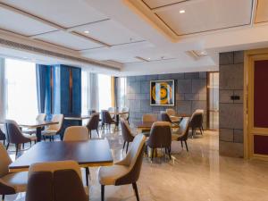 a restaurant with tables and chairs in a room at Qingdao Likelai Garden Hotel in Qingdao