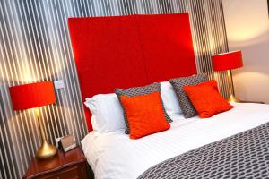 a bedroom with a bed with red and orange pillows at Belmont Hotel Leicester in Leicester