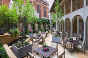 un patio al aire libre con mesas, sillas y árboles en The Rittenhouse Hotel, en Filadelfia