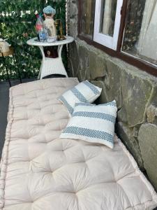 a bed sitting next to a stone wall with pillows at Lee's Grandma's Will Cottage in Kalimpong