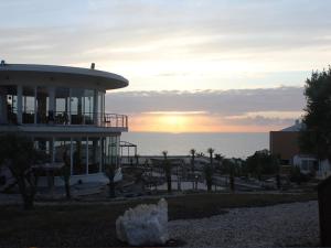 a building on the beach with a sunset in the background at Noiva do Mar in Lourinhã