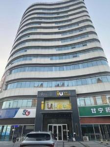 ein hohes Gebäude mit einem davor geparkt in der Unterkunft IU Hotel Shijiazhuang Development Zone Tianshanhaijie East 4th Provincial Hospital in Shijiazhuang
