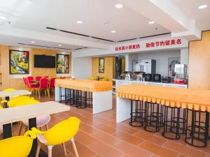 a restaurant with tables and yellow chairs at IU Hotel Baoding Yuhua East Road Passenger Center in Baoding