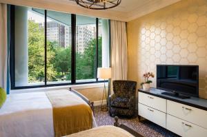 a bedroom with a bed and a tv and a window at The Rittenhouse Hotel in Philadelphia