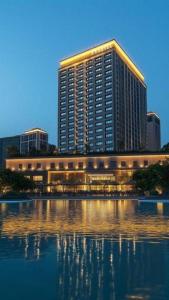 a large building with a reflection in a body of water at JTOUR Inn Wuhan Wusheng Road Metro CapitaLand Plaza in Wuhan