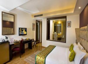 a hotel room with a bed and a desk in a room at Hotel The Tulip international Near Delhi Airport,A block Road no 4 street no 10 mahipalpur new delhi in New Delhi