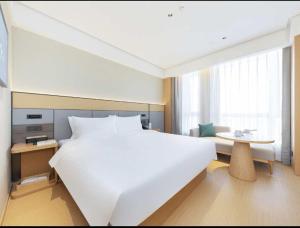 a bedroom with a large white bed and a table at All Seasons Beijing Capital Airport Liqiao Hotel in Beijing +7 photos