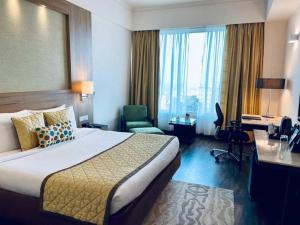 Una habitación de hotel con una cama grande y un escritorio. en Hotel The Tulip international Near Delhi Airport,A block Road no 4 street no 10 mahipalpur new delhi, en Nueva Delhi