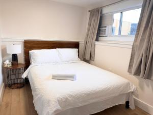 ein Schlafzimmer mit einem weißen Bett und einem Fenster in der Unterkunft Newly renovated 2-bedroom, 1-bathroom suite with private entrance in West Kelowna