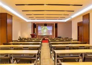an empty lecture hall with tables and a projection screen at Borrman Hotel Dongguan Dongcheng Wanda Plaza Tianbao Metro Station in Dongguan