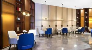 une salle à manger avec des tables et des chaises bleues et blanches dans l'établissement E-Cheng Hotel Yangjiang Baili Plaza, à Yangjiang