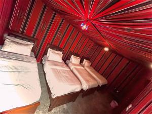 two beds in a room with red curtains at Little Petra Bedouin Camp in Al Ḩayy +166 photos