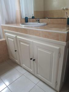 a bathroom vanity with a sink and a mirror at Ti kaz Annah in Le Tampon