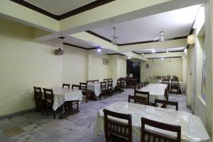 une salle à manger vide avec des tables, des chaises et un chercheur de table dans l'établissement Hotel O Buddha Statue Gaya Formerly Uruvela International, à Bodh Gaya