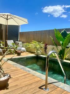 a swimming pool in a backyard with an umbrella at Villa Familly in Saint-Paul