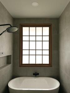 une baignoire dans une salle de bain avec une fenêtre dans l'établissement Kiyomizu Onsen & Glamping Resort Saraburi, à Ban Nong Nak