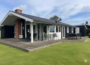 ein Haus mit einer Terrasse mit Stühlen und Tischen in der Unterkunft Fantastic View And 150 Meters To The Beach in Sønderby