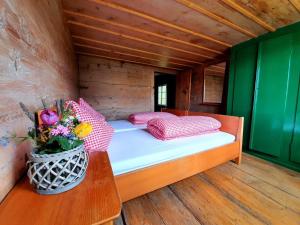 a bed in a wooden room with a vase of flowers at Ferienhaus Unteraxen in Sisikon