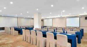 einen Konferenzraum mit blauen Tischen und Stühlen sowie einem Bildschirm in der Unterkunft Vienna Hotel Shandong Qingdao Taidong Pijiu Street Liaoning Road in Qingdao