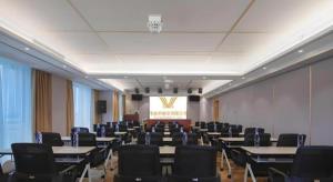 a conference room with tables and chairs and a projector at Vienna Hotel Shandong Liaocheng High-Tech Zong Yueji Park in Liaocheng