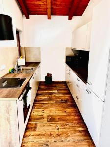 a kitchen with white cabinets and a wooden floor at Haus Auszeit in Buchau +24 photos