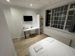 a bedroom with a bed and a desk with a television at White Rose Hotel & Restaurant - Leeds in Leeds