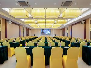 ein Konferenzraum mit Tischen und Stühlen und einer Leinwand in der Unterkunft Vienna Hotel Guangxi Wuzhou High-Tech in Wuzhou