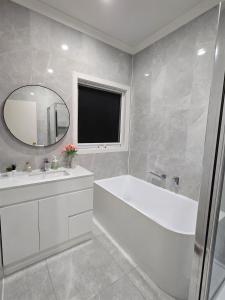 Un baño con bañera, lavabo y espejo. en Beautiful & Modern 2BR Residence in Doncaster East, en Doncaster East
