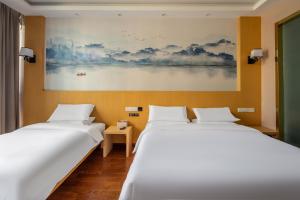 two beds in a room with a painting on the wall at Meiwan Inn in Jiaxing